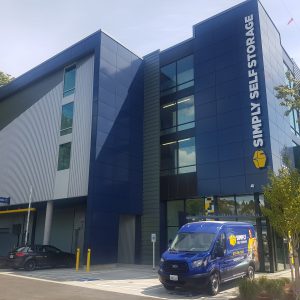 3 story building with navy blue metal cladding with a van in front of the building